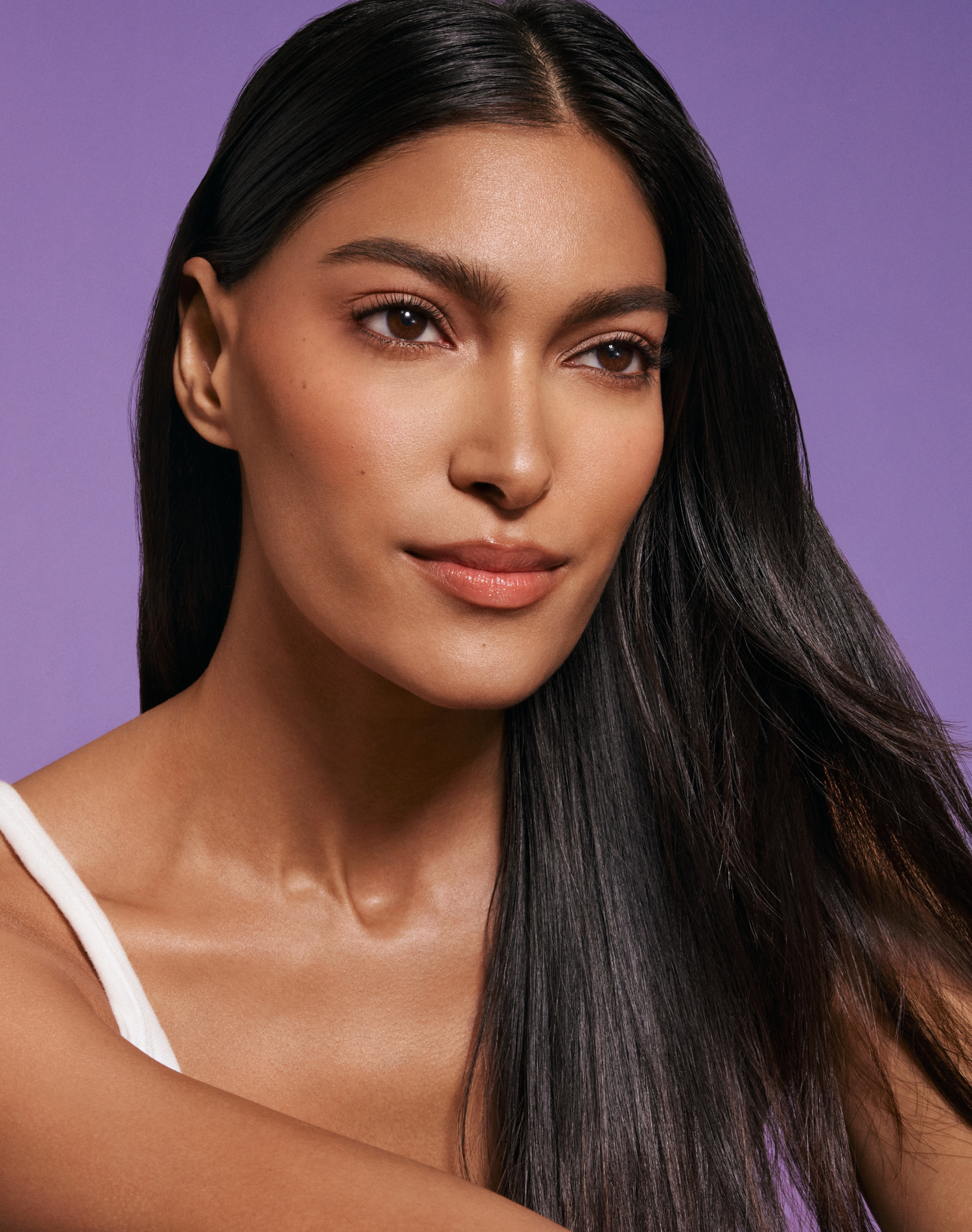 confident woman with flawless skin and sleek black hair embodying fearless beauty against purple background