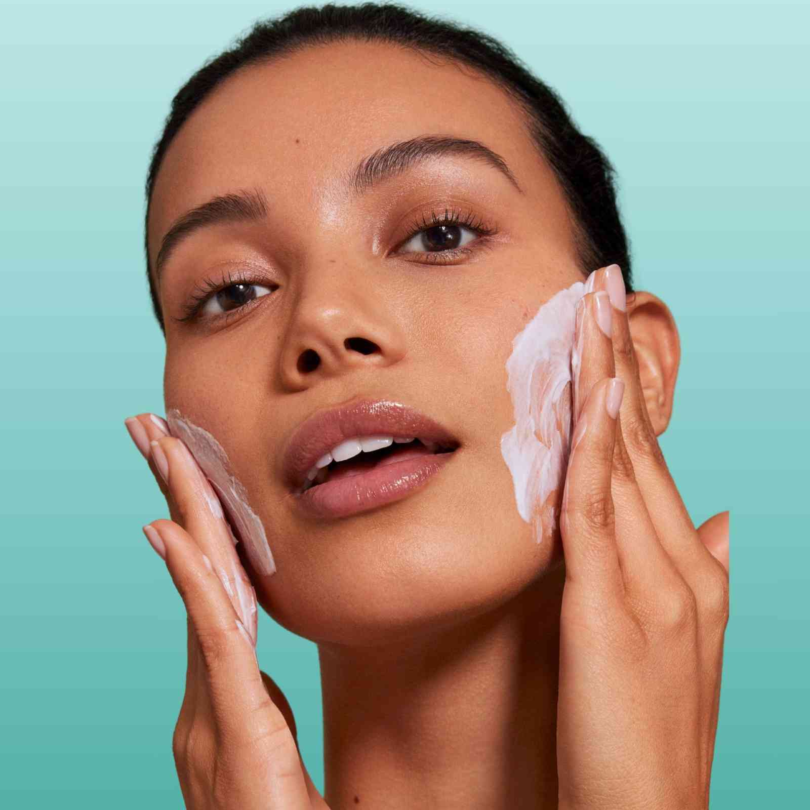 Woman applying creamy DeviDetox® hydrating cleanser to face for clear, smooth skin