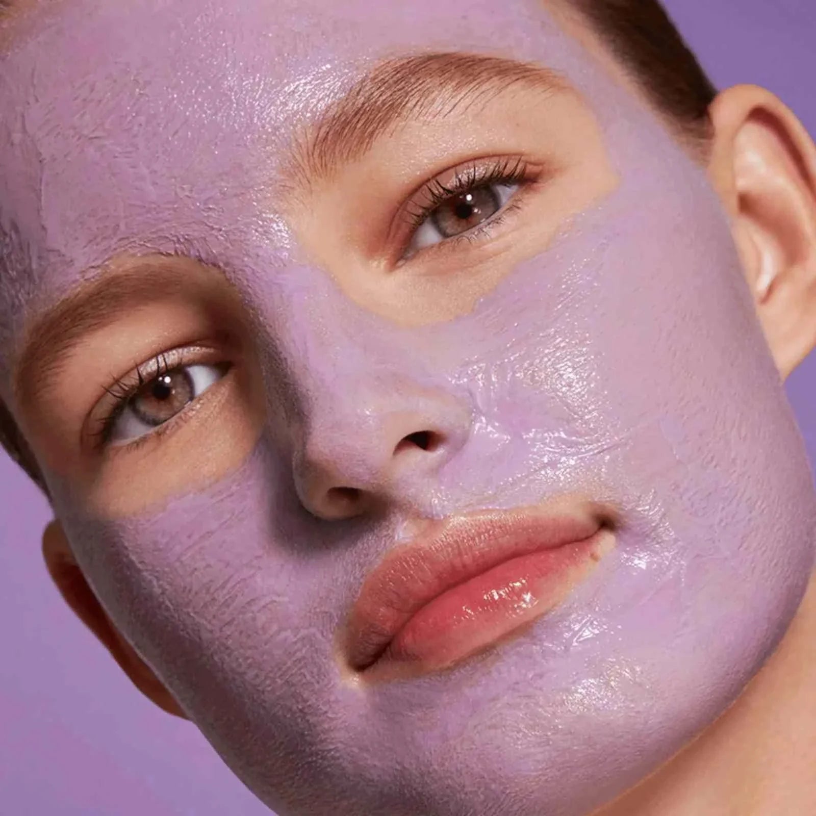 Woman with purple creamy detox clay mask applied on face for clear, smooth, and radiant skin