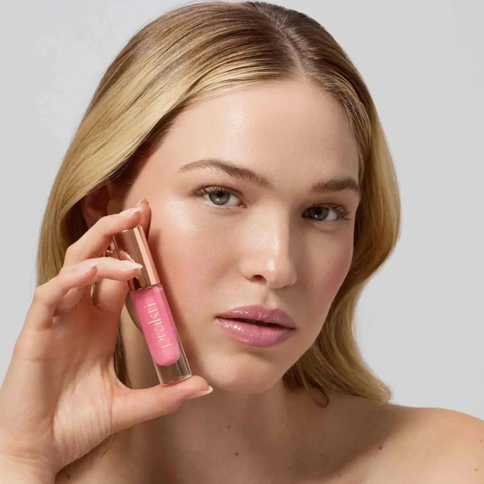 Woman holding KhushiKiss lip oil for smooth, nourished lips