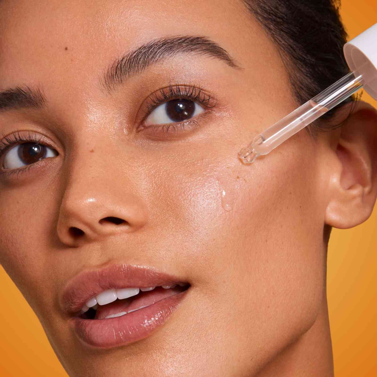 woman applying lightweight serum with dropper for glowing skin close-up