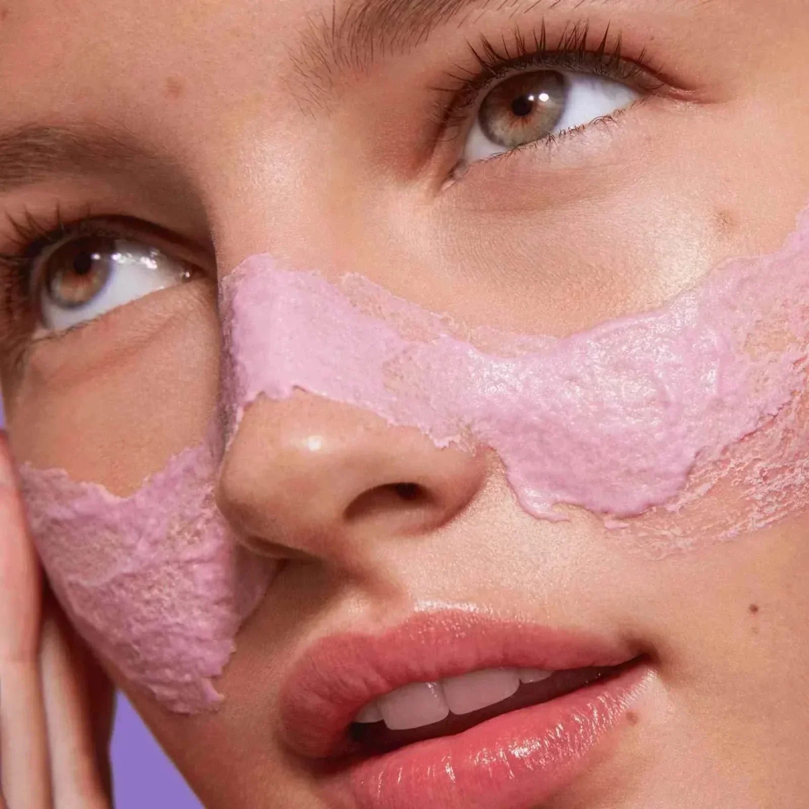 close-up of a woman with pink hydrating mask applied on cheeks showcasing skincare set results